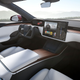 The front seats in a Tesla car with the large infotainment screen on the dash
